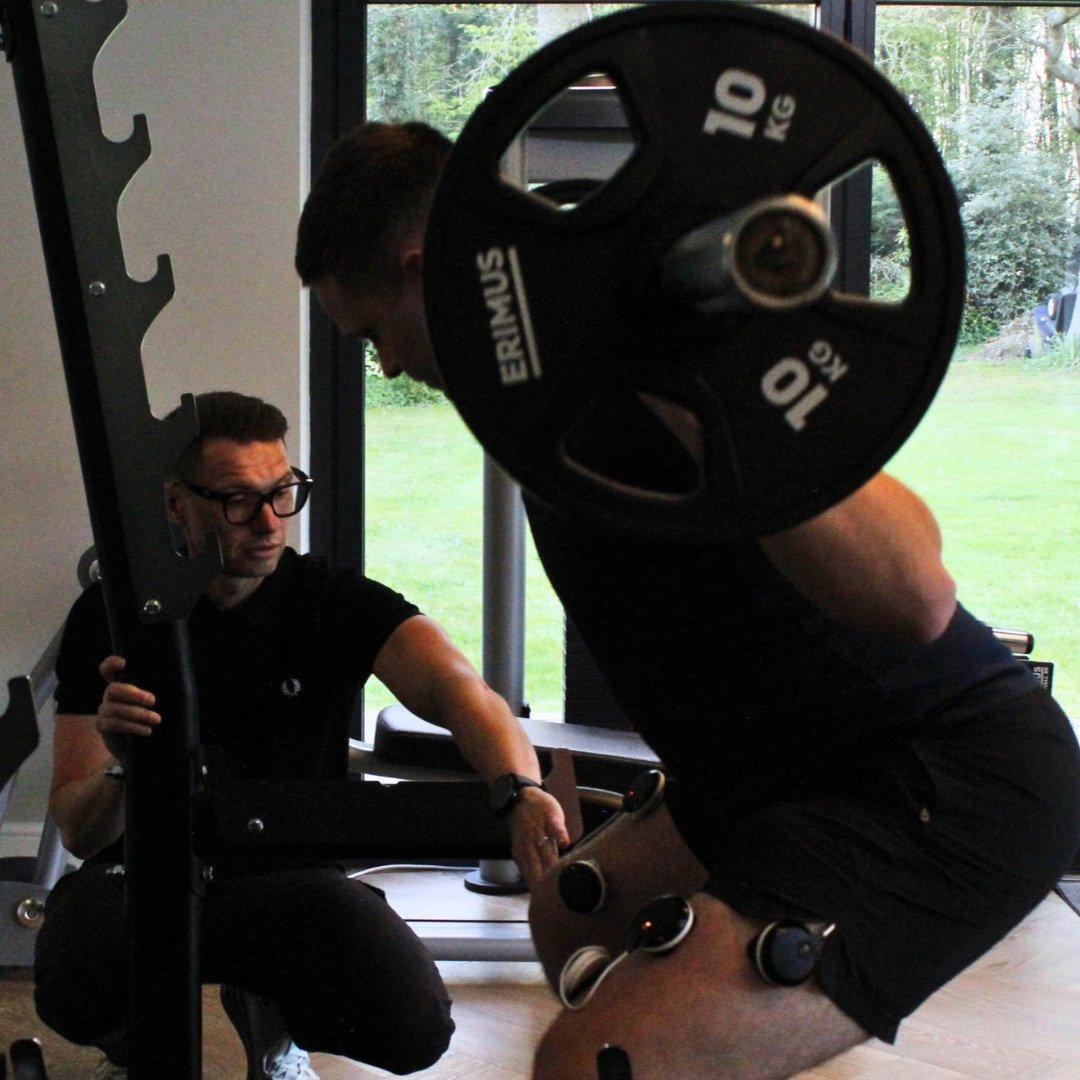 Physiotherapist supervising strength and rehabilitation exercises in a gym environment