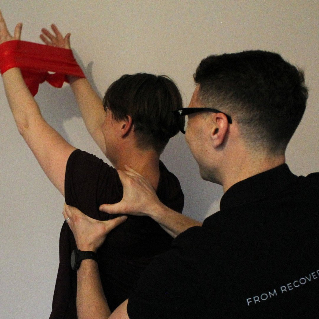 Physiotherapist assisting patient with shoulder rehabilitation exercises using resistance band