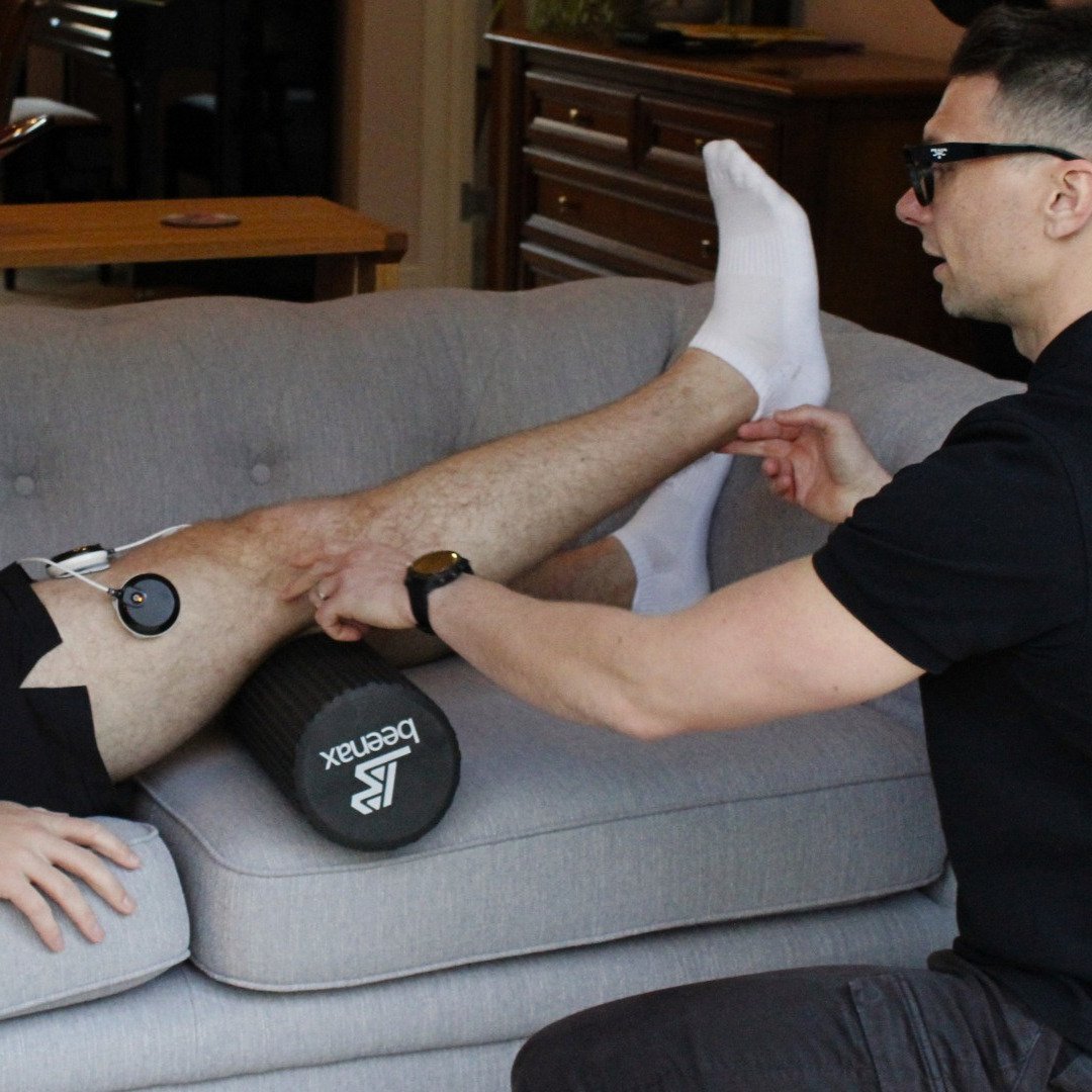 Physiotherapist assessing leg mobility during a home rehabilitation session